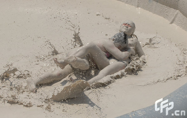 Two females are entangled in dogfight during a distinctive Women's Mud Wrestling Match, as some 40 female contestants from both China and overseas take part in this very amusing sport with the skin-friendly slurry and mud from the deep sea, in Wuhan, central China's Hubei Province, May 3, 2009.[Xiong Bo/CFP]