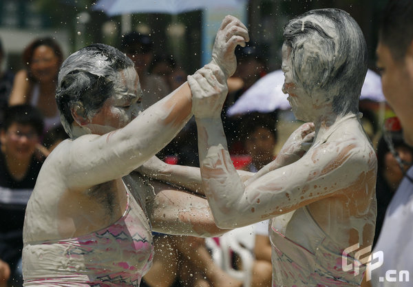 Two females are entangled in dogfight during a distinctive Women's Mud Wrestling Match, as some 40 female contestants from both China and overseas take part in this very amusing sport with the skin-friendly slurry and mud from the deep sea, in Wuhan, central China's Hubei Province, May 3, 2009.[Xiong Bo/CFP]