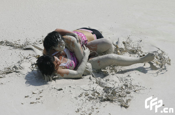 Two females are entangled in dogfight during a distinctive Women's Mud Wrestling Match, as some 40 female contestants from both China and overseas take part in this very amusing sport with the skin-friendly slurry and mud from the deep sea, in Wuhan, central China's Hubei Province, May 3, 2009.[Xiong Bo/CFP]