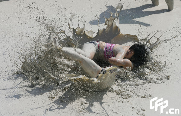 Two females are entangled in dogfight during a distinctive Women's Mud Wrestling Match, as some 40 female contestants from both China and overseas take part in this very amusing sport with the skin-friendly slurry and mud from the deep sea, in Wuhan, central China's Hubei Province, May 3, 2009.[Xiong Bo/CFP]