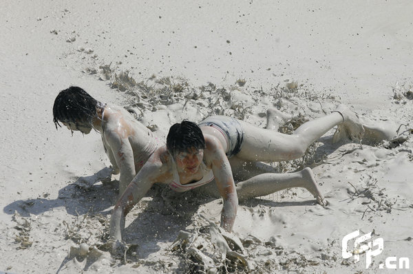 Two females are entangled in dogfight during a distinctive Women's Mud Wrestling Match, as some 40 female contestants from both China and overseas take part in this very amusing sport with the skin-friendly slurry and mud from the deep sea, in Wuhan, central China's Hubei Province, May 3, 2009.[Xiong Bo/CFP]