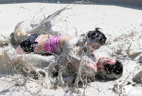 Two females are entangled in dogfight during a distinctive Women's Mud Wrestling Match, as some 40 female contestants from both China and overseas take part in this very amusing sport with the skin-friendly slurry and mud from the deep sea, in Wuhan, central China's Hubei Province, May 3, 2009.[Xiong Bo/CFP]