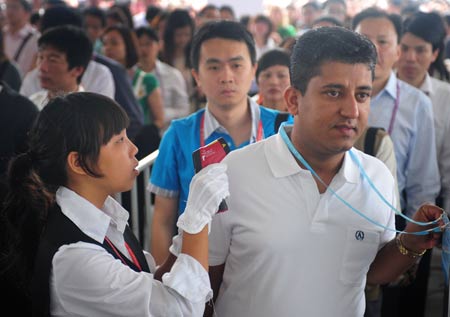 A staff member checks a visiter's body temperature during the third phase of the 105th Canton Fair in Guangzhou, capital of south China's Guangdong Province, May 3, 2009. The third phase of the 105th Canton Fair, China's largest trade event, began Sunday with preventive measures against the A/H1N1 flu. (Xinhua/Lu Hanxin)