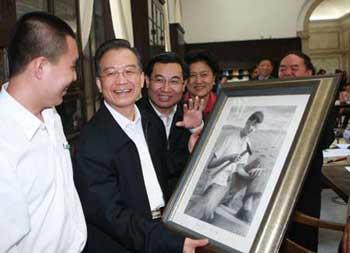 Chinese Premier Wen Jiabao (2nd L) receives a paint gift from a student of Tsinghua University, in Beijing, capital of China, May 3, 2009. Wen attended a symposium on Sunday with student representatives from Tsinghua University, who have chosen to work in the vast western regions or at the grassroots level after graduation. [Ju Peng/Xinhua ] 