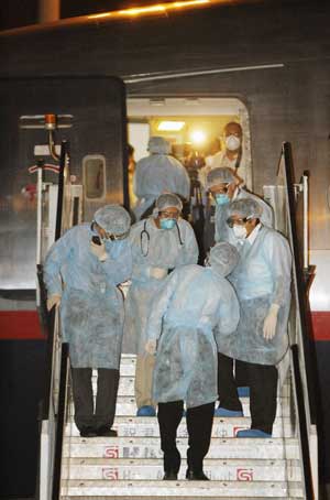 Mexican medical workers cald in surgical suits stand on the gangway of Mexican charter flight at Hong Kong International Airport in Hong Kong, south China, May 6, 2009. The charter flight, which had picked up quarantined Mexicans from Shanghai, Beijing and Guangzhou, arrived in Hong Kong early Wednesday morning to pick up another 12 Mexican tourists, and then left China for Mexico. (Xinhua/Zhou Lei)