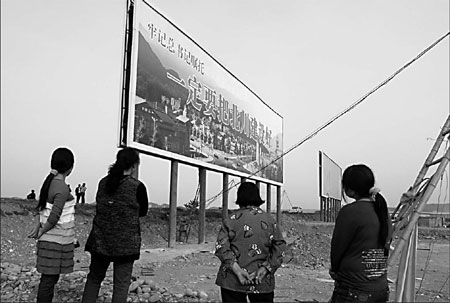 People read a signboard on Saturday at the site where construction of the new Beichuan county seat will begin. The county in Sichuan province was devastated by last May's 8.0-magnitude earthquake. [China Daily]