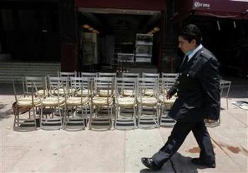 A man walks in front of a closed restaurant in Mexico City May 4, 2009. Mexican businesses will resume regular activities as planned on Wednesday after a five-day shutdown due to the fatal flu outbreak, the health minister said on Monday. 