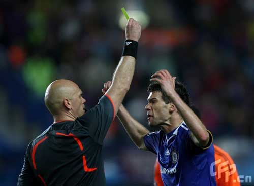 Referee Tom Ovrebo (L) books Chelsea's Michael Ballack for dissent.