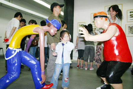 Visitors appreciate a group of dummy figures exhibited in the 2009 Graduates' Works Show of the Art College of the Nanjing Arts Institute, at the Jiangsu Art Gallery in Nanjing, capital of east China's Jiangsu Province, May 6, 2009. [Xinhua/Xun Hai]