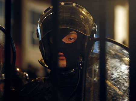 A riot policeman watches protestors after clashing at the city's police base in Tbilisi, May 6, 2009. Police and protesters clashed in Georgia on Wednesday during a month-long opposition campaign to oust President Mikheil Saakashvili, stoking fears of unrest after a failed military mutiny.