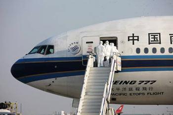 Inspectors walk aboard the chartered plane from Mexico to check the health of Chinese citizens from Mexico after the plane arrived in Shanghai on May 6, 2009. The chartered plane sent to fetch Chinese citizens from Mexico arrived in Shanghai Wednesday afternoon, with 98 passengers and 21 crew members on board. [Xing Guangli/Xinhua] 