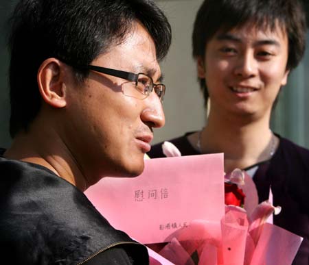 A Chinese passenger (L) from the Mexico City-Shanghai flight AM098, where a Mexican man was confirmed to be infected with influenza A/H1N1, receives flowers and a letter as the quarantine ends in Shanghai, east China, May 7, 2009. Chinese health authorities on Thursday started lifting a seven-day quarantine on passengers who took the same flight with the Mexican man. [Li Wen/Xinhua]