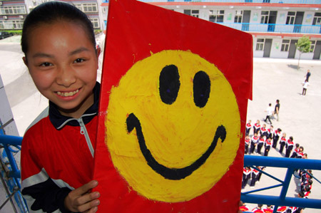 A girl shows a board with a smiling face during an activity to celebrate the upcoming World Smile Day at No. 10 Middle School in Xingtai, north China&apos;s Hebei Province, May 7, 2009. The World Smile Day falls on May 8. (Xinhua/Chen Lei)