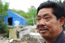 Li Chuanfu stands in the ruins of his farmhouse that was destroyed by the Sichuan earthquake on May 12, 2008. In the background is the tent Mr Li and his family lived in for three months after the quake. [John Sexton, China.org.cn, May 9 2009] 