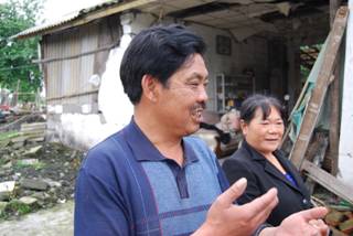 Li Chuanfu and his wife explain the problems they face in their efforts to rebuild their farmhouse, which was destroyed in the Sichuan earthquake on May 12, 2008. In the background is the front section of the house - the only part still standing. [John Sexton, China.org.cn, May 9 2009]