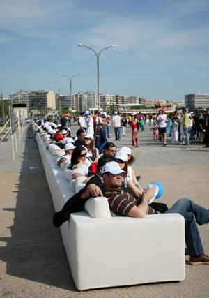 People sit on a super-long sofa in Thessaloniki, Greece, May 9, 2009. This 64.75-meter-long sofa set the Guinness World Records for being the longest sofa in the world. [Xinhua/AFP] 