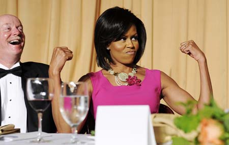 U.S. first lady Michelle Obama flexes her arms in response to a joke about her habit of wearing sleeveless dresses during the White House Correspondents' Association Dinner in Washington May 9, 2009.[Xinhua/Reuters]