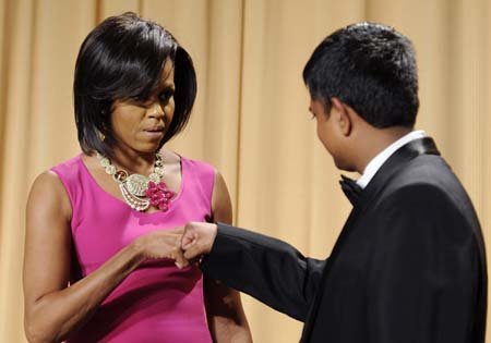 U.S. first lady Michelle Obama (L) gives a fist bump to a journalism scholarship recipient at the White House Correspondents' Association Dinner in Washington May 9, 2009.[Xinhua/Reuters]