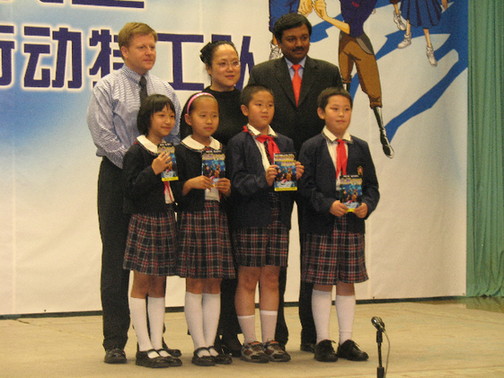 Anand Selva (1st R), Yinchao (2nd R) and student representatives pose for a photo after Selva, on behalf of Citi China, presented over 300 comic books to students at the Primary School Attached to Peking University. [China.org.cn]