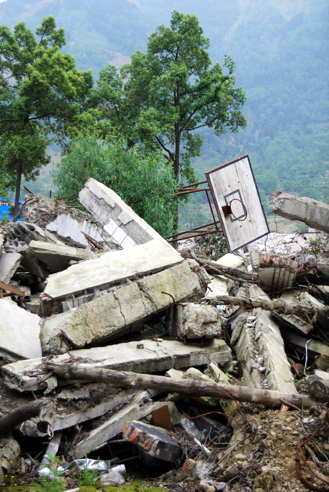 A basketball hoop rests on the ruins of one of the buildings of Beichuan Middle School. [John Sexton/China.org.cn]