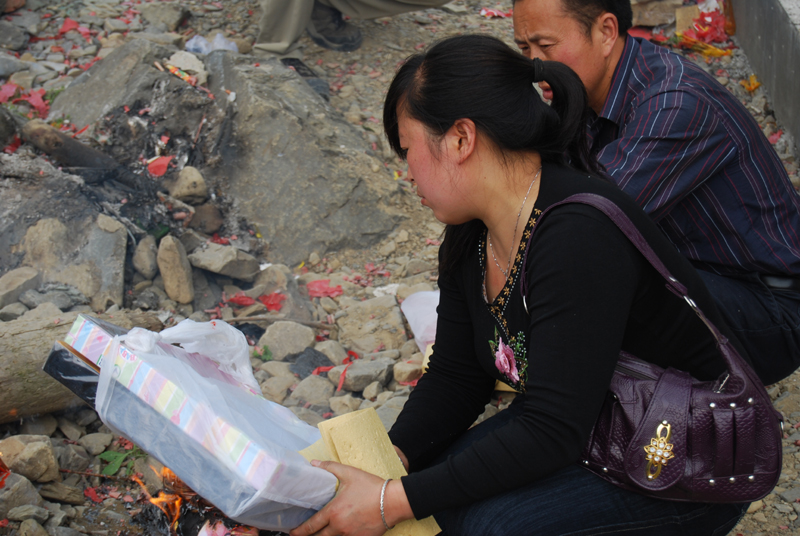 A couple prepare to burn two shirts as an offering in Beichuan on May 11, 2009. [John Sexton/China.org.cn]