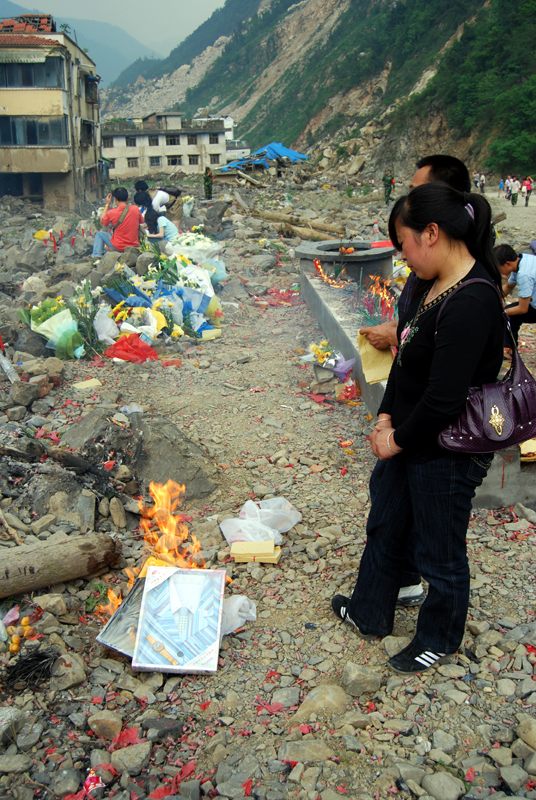 A couple burn two shirts as an offering in Beichuan on May 11, 2009. [John Sexton/China.org.cn]