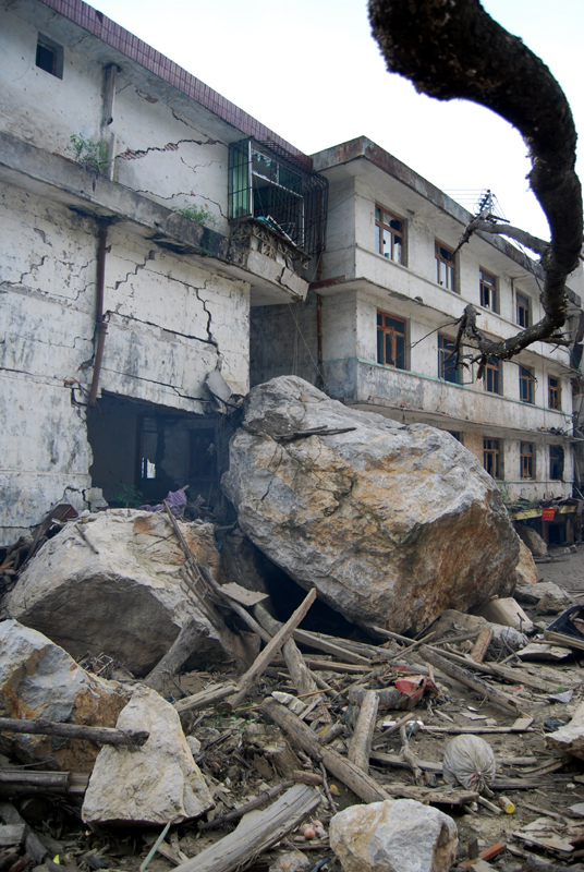 Huge boulders rest alongside ruined buildings in Beichuan. [John Sexton/China.org.cn]