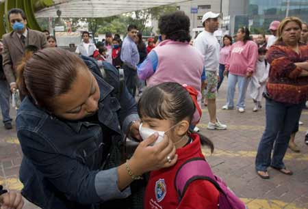 A woman helps her daughter wear the mask before she walks to classroom at a primary school in Mexico City, capital of Mexico, May 11, 2009. Most of Mexican pre-school educational institutions as well as primary and secondary schools resume classes May 11 after days of closure due to the influenza epidemic. [David De la Paz/Xinhua]