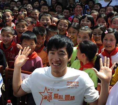 Chinese hurdler Liu Xiang poses for photgraphs with quake zone pupils at a primary school in Beichuan county, southwest China's Sichuan province, Monday May 11, 2009. [Xinhua]