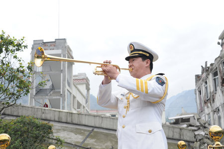 A man plays a trumpet at the beginning of the ceremony to mark the first anniversary of May 12 Earthquake in Yingxiu Township of Wenchuan County, southwest China&apos;s Sichuan Province, May 12, 2009. [Xinhua]