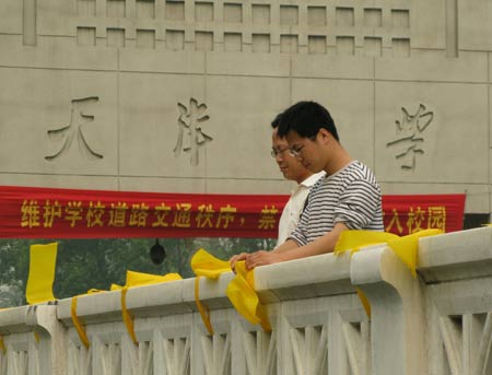 Voluteers fasten yellow ribbons on handrails outside Tianjin University in north China's Tianjin, May 12, 2009. Volunteers tied thousands of yellow ribbons on buses, buildings and trees as a way to commemorate the victims of the May 12, 2008 Wenchuan earthquake.[Xinhua]