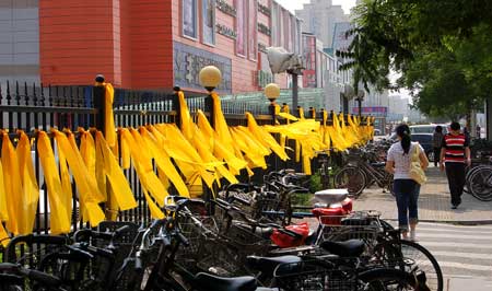 Pedestrians walk past fences tied with yellow ribbons on a street in north China's Tianjin, May 12, 2009. Volunteers tied thousands of yellow ribbons on buses, buildings and trees as a way to commemorate the victims of the May 12, 2008 Wenchuan earthquake.[Xinhua]