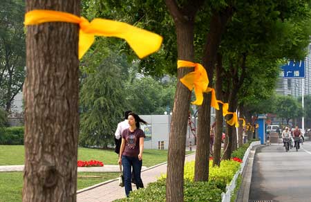 Pedestrians walk past trees tied with yellow ribbons on a street in north China's Tianjin, May 12, 2009. Volunteers tied thousands of yellow ribbons on buses, buildings and trees as a way to commemorate the victims of the May 12, 2008 Wenchuan earthquake.[Xinhua]