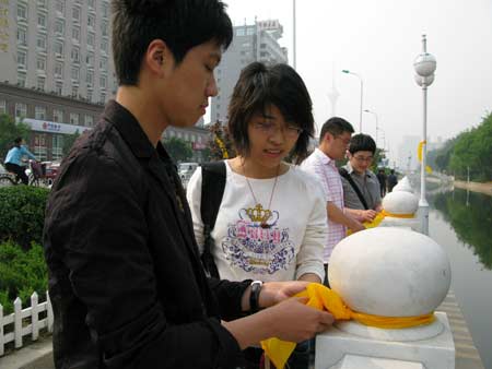 Volunteers tie yellow ribbons to handrails of a bridge in north China's Tianjin, May 12, 2009. Volunteers tied thousands of yellow ribbons on buses, buildings and trees as a way to commemorate the victims of the May 12, 2008 Wenchuan earthquake. [Xinhua]