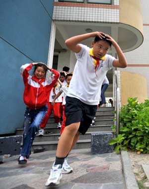 Students take part in a quake rescue drill at Jingcheng Experimental School in Hangzhou, capital of Zhejiang Province in east China, May 12, 2009, China's first National Disaster Prevention and Reductin Day on the occasion of the first anniversary of the May 12, 2008 Wenchuan earthquake.[Xinhua]