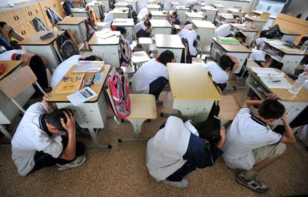 Students take part in a quake rescue drill at Jingcheng Experimental School in Hangzhou, capital of Zhejiang Province in east China, May 12, 2009, China's first National Disaster Prevention and Reductin Day on the occasion of the first anniversary of the May 12, 2008 Wenchuan earthquake. [Xinhua]