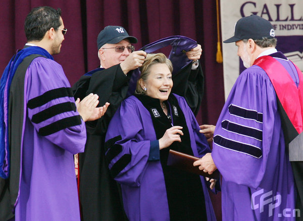 Secretary of State Hillary Rodham Clinton reacts as she is hooded by New York University's Trustees Chair Martin Lipton, second left, as President John Sexton (R) looks on as she receives an honorary Doctor of Law degree during NYU's graduation ceremony held at Yankee Stadium on May 13, 2009 in New York. [CFP] 