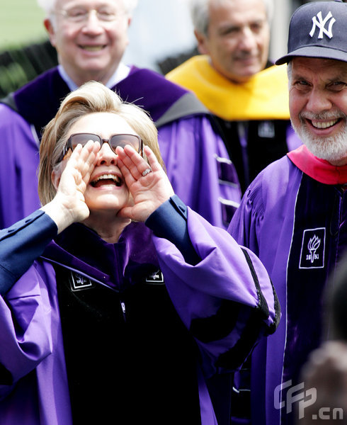 Secretary of State Hillary Rodham Clinton yells out to someone in the crowd as New York University's President John Sexton (R) watches at the conclusion of New York University's graduation ceremony where she received a honorary Doctor of Law degree during the ceremony held at Yankee Stadium on May 13, 2009 in New York.[CFP]