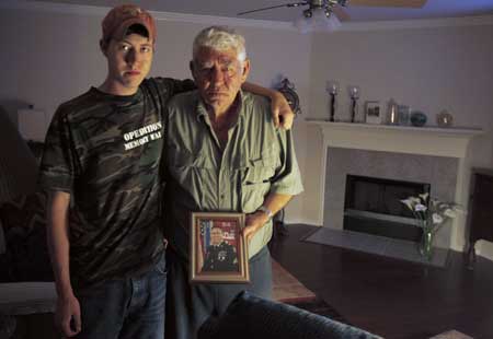 Wilburn Russell, 73, (R), father of Sgt. John M. Russell, stands with his grandson John, 20,(L) as he holds a military portrait of his son who is accused of killing five fellow soldiers in Iraq, inside sergeant Russell's home in Sherman, Texas May 12, 2009.