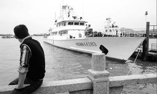 A man looks at Guangdong's largest fishing patrol ship China Yuzheng 44183 anchored at a dock in Zhuhai Thursday 