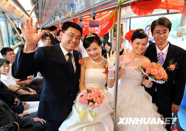 Two couples pose for pictures at a group wedding ceremony held on a subway train in Nanjing, east China's Jiangsu Province on Wednesday, May 13, 2009. The activity is part of cross-Straits group weddings, jointly organized by Nanjing Metro Corporation and Kaohsiung Rapid Transit Corporation. [Photo: Xinhuanet]