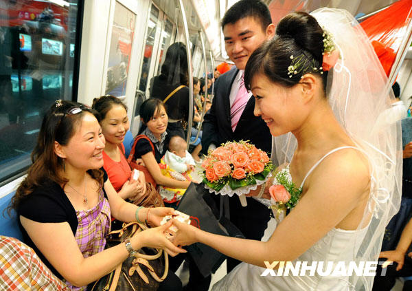 A newlywed gives wedding candies to the passengers on the subway train which started out from Maigaoqiao at around 11:00 a.m. Wednesday, May 13, 2009 in Nanjing, east China's Jiangsu Province. [Photo: Xinhuanet] 