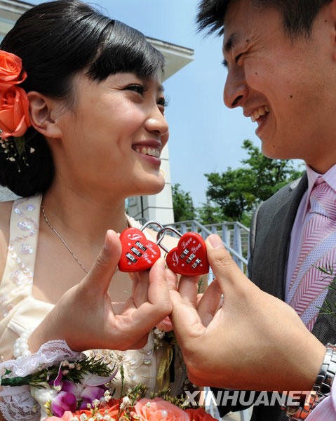 A newlywed couple hold their heart locks with delight during a wedding program on Wednesday, May 13, 2009. A group wedding ceremony held on a subway train in Nanjing, capital of east China's Jiangsu Province in Nanjing subway, part of the cross-Straits group weddings co-organized by Nanjing Metro Corporation and Kaohsiung Rapid Transit Corporation. [Photo: Xinhuanet] 