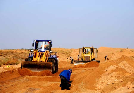 People manipulate bulldozers to work in Ulan Buh Desert of north China's Inner Mongolia Autonomous Region, May 12, 2009. China starts to build the first road through the desert recently. With the length of 71.6 kilometres, the road will be put into use on September 30. (Xinhua/Ren Junchuan)