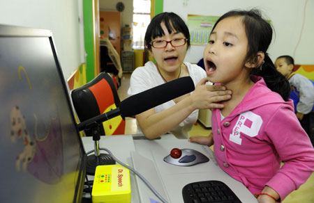 Zhe Ping teaches her deaf student Lu Xinlei to pronounce in a special education nursery school in Shenyang, May 13, 2009. The nursery school started in 1994, and has taught some 1000 handicapped students during the passed 15 years. (Xinhua/Ren Yong)