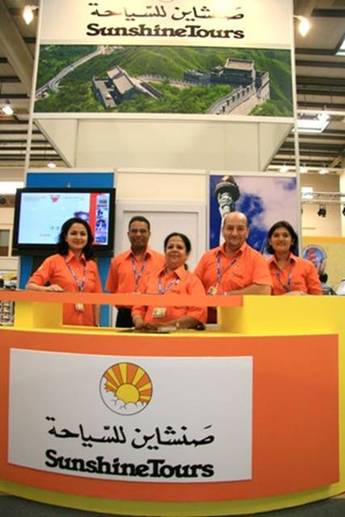 Sunshine Tours’ staff pose for a photo before the Great Wall poster.