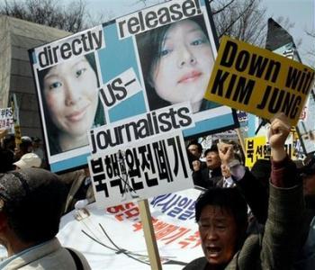 In this photo taken Thursday, April 2, 2009, South Korean protesters shout slogans as they hold pictures of two American journalists Euna Lee and Laura Ling during a rally against North Korea in Seoul, South Korea. North Korea said Thursday, May 14, 2009, it will try two U.S. journalists held in the communist nation for nearly two months on June 4. 