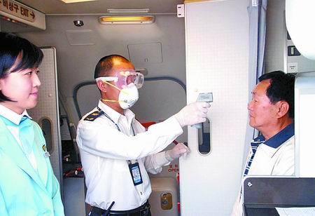 A quarantine officer conducts the temperature test for a passenger who arrives in the Xinzheng International Airport in Henan Province by taking Flight CZ3074 from Hong Kong on May 12. The flow of outbound tourists has almost come to a halt because people are afraid of contracting the A/H1N1 flu virus during travel. [Photo from epaper.dahe.cn]