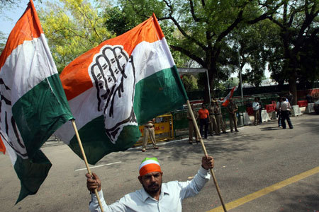 A supporter of Congress party carry party flags as he celebrates in front of the residence of party chief Sonia Gandhi after learning of initial poll results in New Delhi May 16, 2009. India's Prime Minister Manmohan Singh's Congress-led coalition appeared to be heading for a second term after a clear victory in the general election, TV networks projected as votes were counted on Saturday.