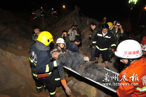 Rescuers carry out an injured person from the ruins of a collapsed residential building at the Jiuzhou Economic Development Zone in Lanzhou, Gansu province May 16, 2009. Part of the building collapsed due to a landslide late Saturday, killing five people and leaving two others missing. [Photo: lzcbnews.com] 